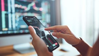 Een belegger kijkt grafieken op een mobiele telefoon