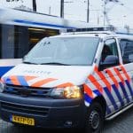 Een politie auto en_of busje in Amsterdam, Nederland, met op de achtergrond een bewegende tram