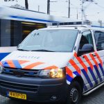 Een politie auto en_of busje in Amsterdam, Nederland, met op de achtergrond een bewegende tram