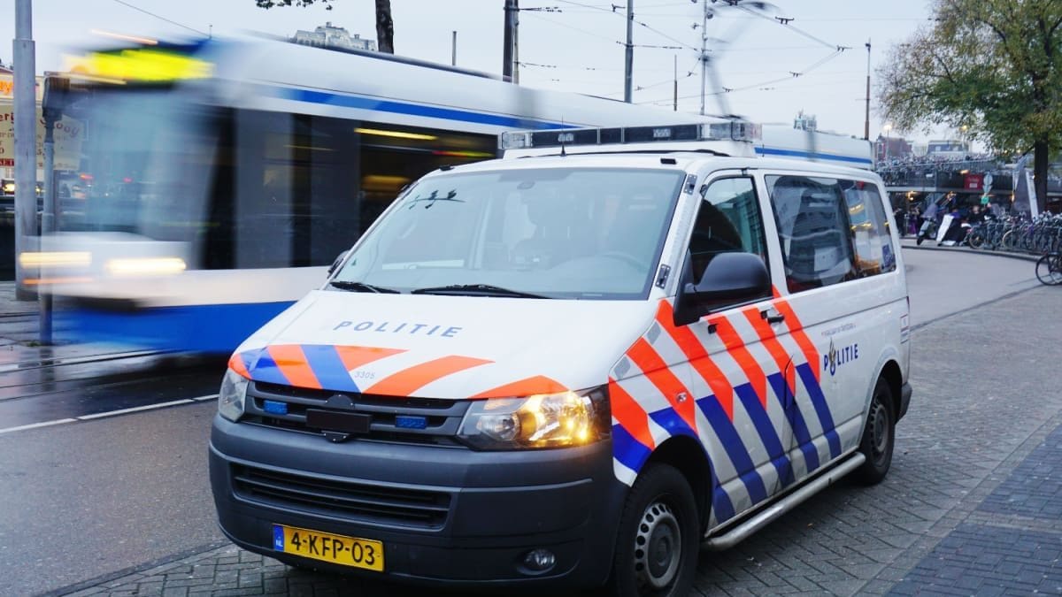 Een politie auto en_of busje in Amsterdam, Nederland, met op de achtergrond een bewegende tram