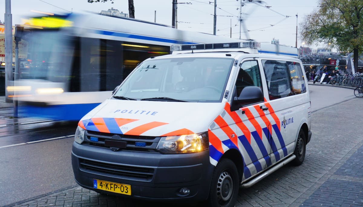 Een politie auto en_of busje in Amsterdam, Nederland, met op de achtergrond een bewegende tram