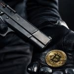 Een overvaller met een pistool houdt een bitcoin munt vast