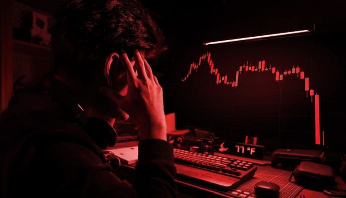 Een afbeelding met een rood filter waarbij een cryptohandelaar gefrustreerd en gestresst naar een hard gecrashte crypto koers kijkt