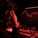 Een afbeelding met een rood filter waarbij een cryptohandelaar gefrustreerd en gestresst naar een hard gecrashte crypto koers kijkt