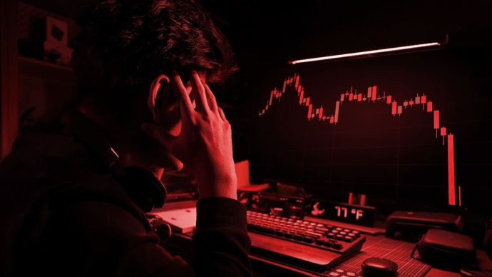 Een afbeelding met een rood filter waarbij een cryptohandelaar gefrustreerd en gestresst naar een hard gecrashte crypto koers kijkt