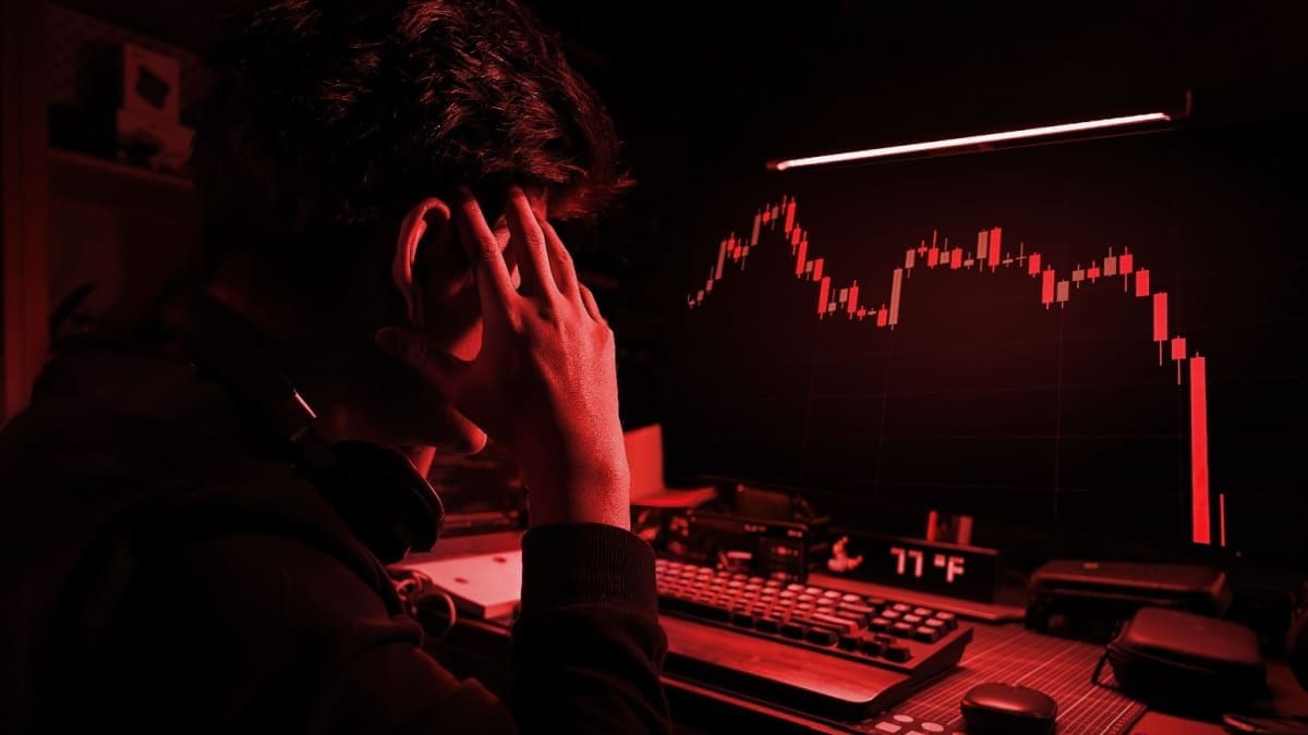 Een afbeelding met een rood filter waarbij een cryptohandelaar gefrustreerd en gestresst naar een hard gecrashte crypto koers kijkt