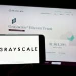 Een afbeelding met het logo van Grayscale, een van de grootste crypto vermogensbeheerders, met op de achtergrond de website van het Grayscale bitcoin (BTC) fonds