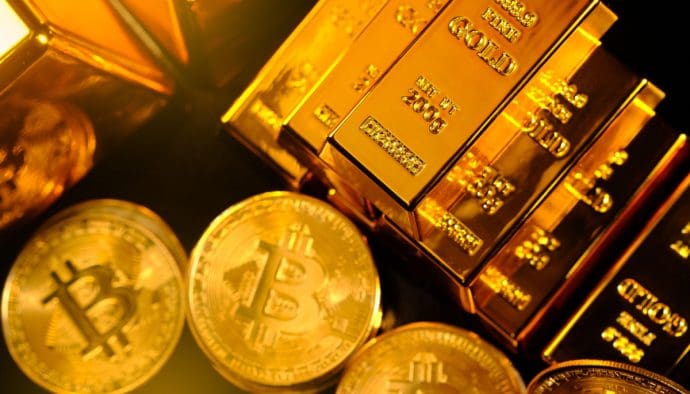 Een afbeelding van bitcoin (BTC) munten naast een aantal pure baren van goud