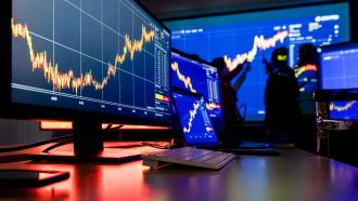 Een afbeelding van meerdere beeldschermen met koersen van crypto en aandelen en op de achtergrond beleggers die een koers analyseren