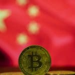 Een bitcoin (BTC) munt op de voorgrond, met op de achtergrond de vlag van China