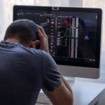 Een crypto of aandelen investeerder zit met zijn handen in zijn haar, omdat hij alles verloren heeft of een grote domper heeft gemaakt
