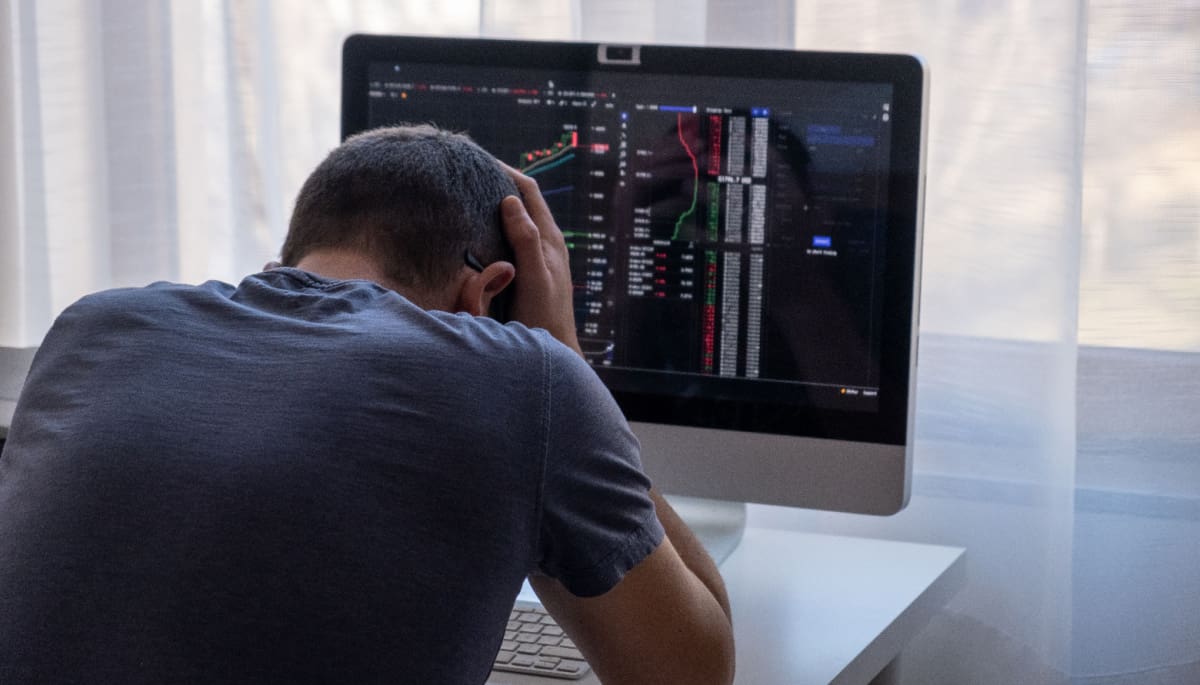 Een crypto of aandelen investeerder zit met zijn handen in zijn haar, omdat hij alles verloren heeft of een grote domper heeft gemaakt