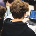 Meerdere studenten werken samen op een laptop aan een hackathon, met software _ code op een laptop