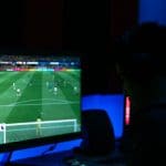 Foto van een man die FIFA speelt op een scherm