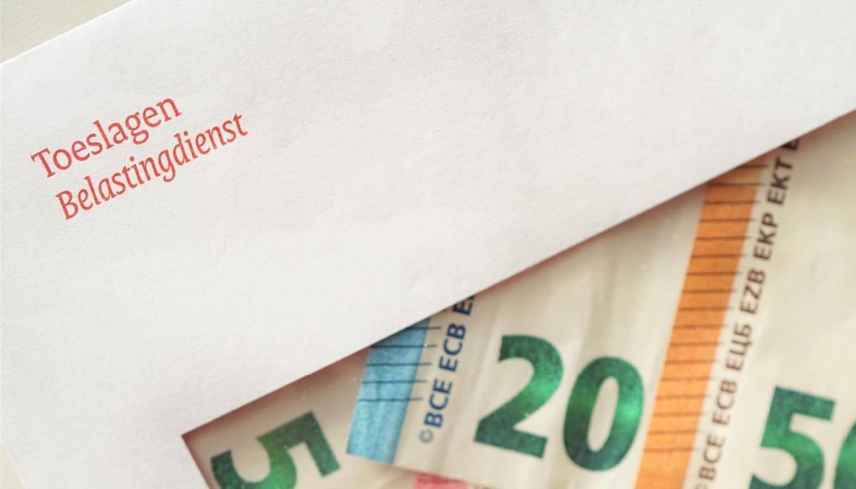 Een envelop van de Belastingdienst met daarin geld