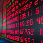 Een afbeelding van rode cijfers op een bord met aandelen en/of crypto koersen