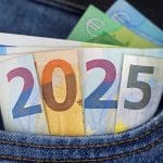 Een aantal euro bankbiljetten die uit een broekzak steken en samen het jaartal 2025 vertonen