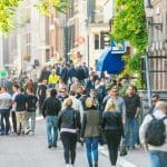 Een afbeelding van Nederlanders en toeristen die lopen door Amsterdam