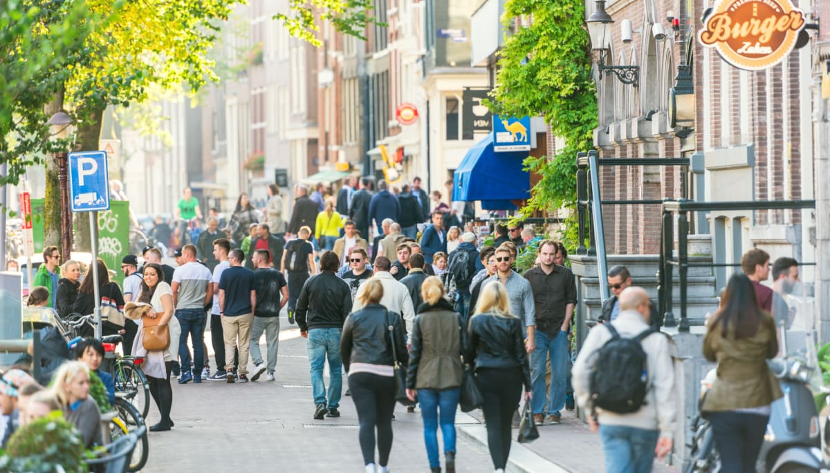 Een afbeelding van Nederlanders en toeristen die lopen door Amsterdam