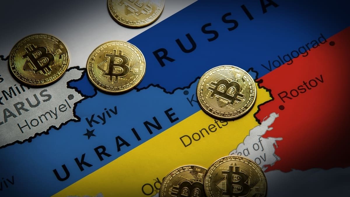 Een afbeelding van een landkaart met Rusland en Oekraïne, met daartussen bitcoinmunten verspreid