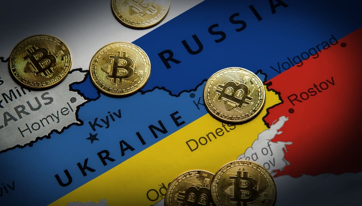 Een afbeelding van een landkaart met Rusland en Oekraïne, met daartussen bitcoinmunten verspreid