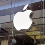 Een afbeelding van het Apple logo op een kantoor, met werkende mensen op de achtergrond