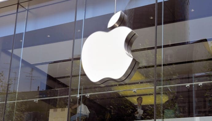 Een afbeelding van het Apple logo op een kantoor, met werkende mensen op de achtergrond