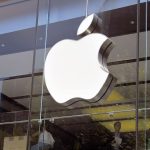 Een afbeelding van het Apple logo op een kantoor, met werkende mensen op de achtergrond
