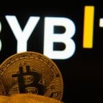 Een afbeelding van het logo van cryptobeurs Bybit op de achtergrond, met op de voorgrond een aantal bitcoin (BTC) munten
