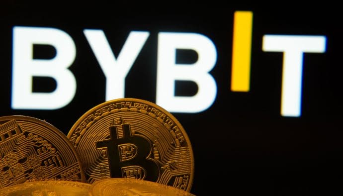 Een afbeelding van het logo van cryptobeurs Bybit op de achtergrond, met op de voorgrond een aantal bitcoin (BTC) munten