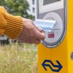 Een afbeelding van het openbaar vervoer waarbij een Nederlander een ov-chipkaart gebruikt om in te checken bij NS
