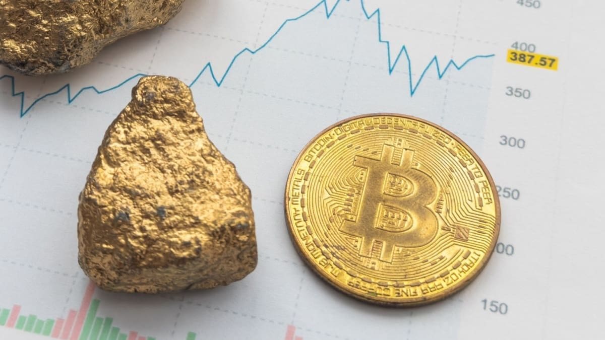 Een goudklomp en een bitcoin munt naast elkaar met een grafiek op de achtergrond