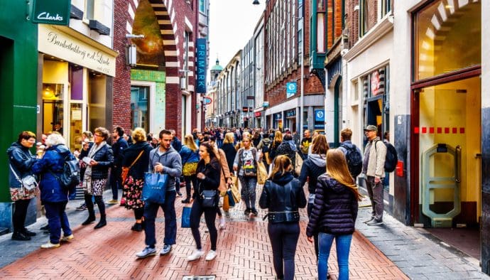 Een afbeelding van Nederlanders die wandelen en winkelen in de straten van Amsterdam