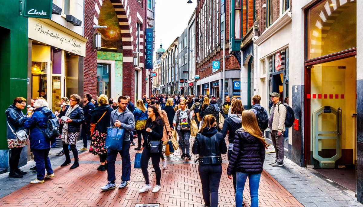 Een afbeelding van Nederlanders die wandelen en winkelen in de straten van Amsterdam