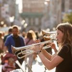 Een afbeelding van een aantal straatmuzikanten die met trompetten proberen geld op te halen