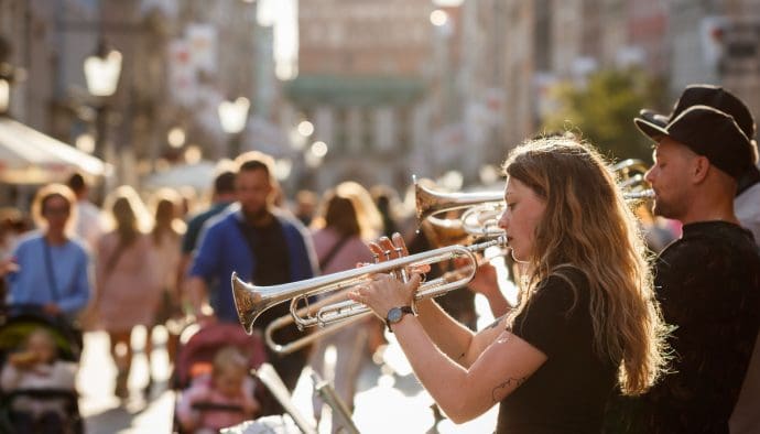 Een afbeelding van een aantal straatmuzikanten die met trompetten proberen geld op te halen