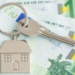 Een afbeelding van een huissleutel met een huis eraan, en op de achtergrond euro bankbiljetten, wat de woningmarkt en de bijbehorende stijgende prijzen moet representeren
