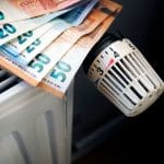 Een afbeelding van eurobiljetten op een verwarming in een huishouden, die vaste lasten moet representeren