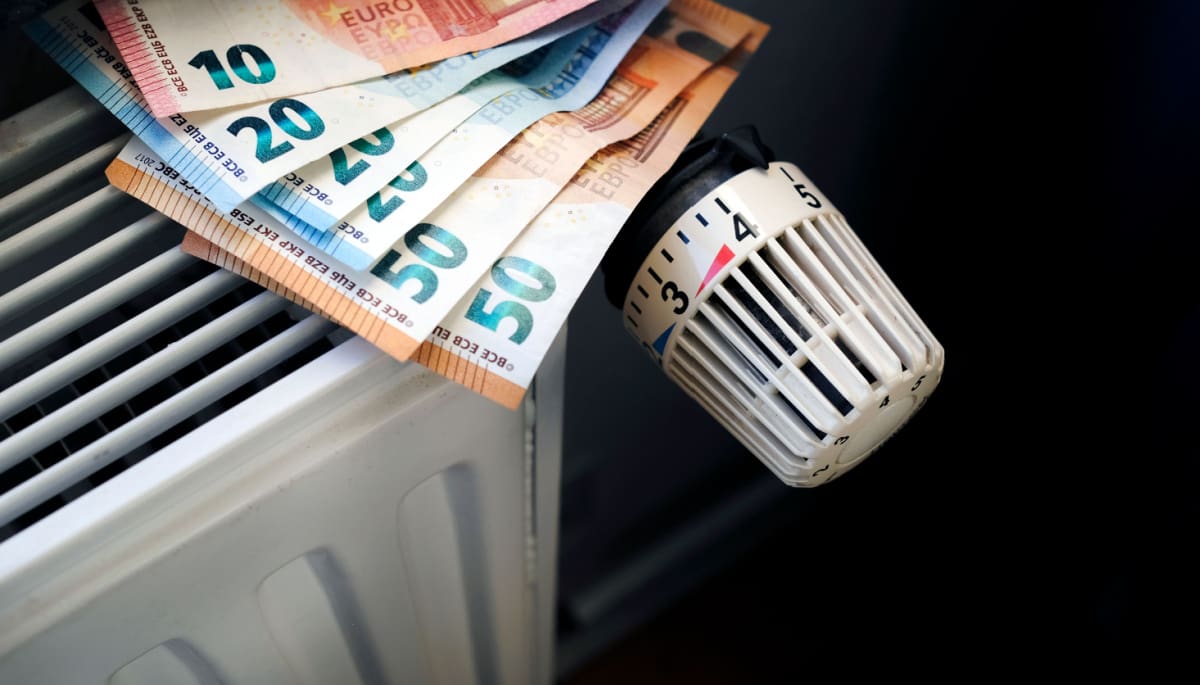 Een afbeelding van eurobiljetten op een verwarming in een huishouden, die vaste lasten moet representeren