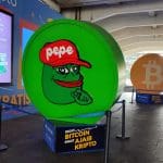 Een fysieke afbeelding van pepe coin (PEPE), een van de grootste memecoins van de cryptomarkt, op een crypto conferentie