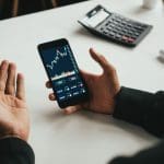 Man trading grafiek telefoon bureau Duizenden Nederlanders verdienen 114% met gratis ‘crypto-supercomputer’