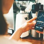 Vrouw bekijkt koersgrafiek op telefoon telefoon koersgrafiek