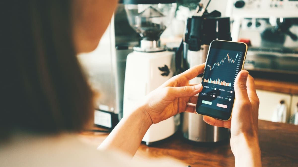 Vrouw bekijkt koersgrafiek op telefoon telefoon koersgrafiek