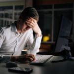 man baalt achter computer