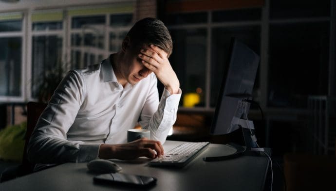 man baalt achter computer