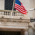 Een afbeelding van de aandelenbeurs van New York, met daarbij een straatbordje met Wall Street
