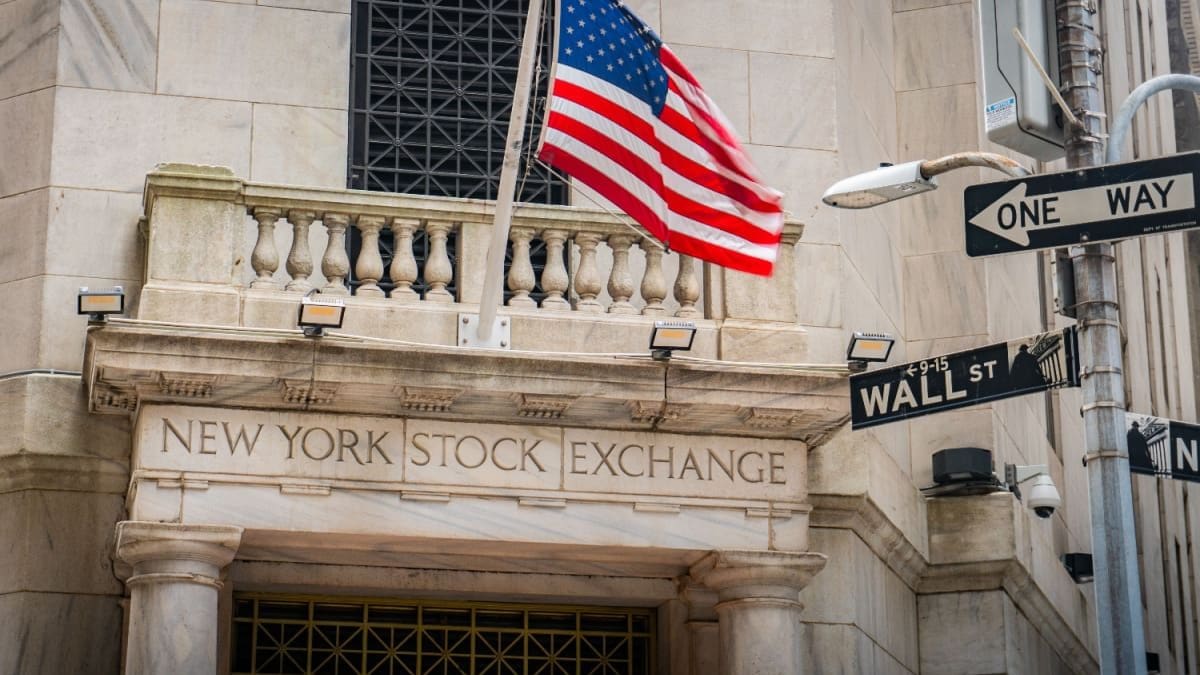 Een afbeelding van de aandelenbeurs van New York, met daarbij een straatbordje met Wall Street
