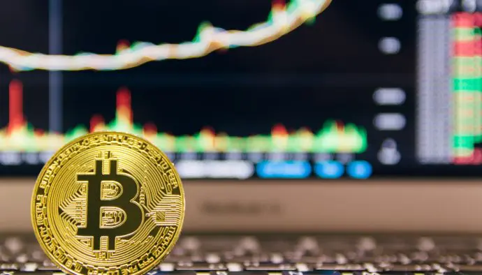 Een afbeelding van de munt van de grootste crypto bitcoin (BTC) met op de achtergrond een stijgende groene grafiek