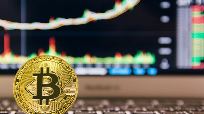 Een afbeelding van de munt van de grootste crypto bitcoin (BTC) met op de achtergrond een stijgende groene grafiek