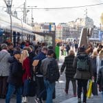 Een afbeelding van een groep mensen van alle leeftijdsgroepen bij een tram, Amsterdam, Nederland